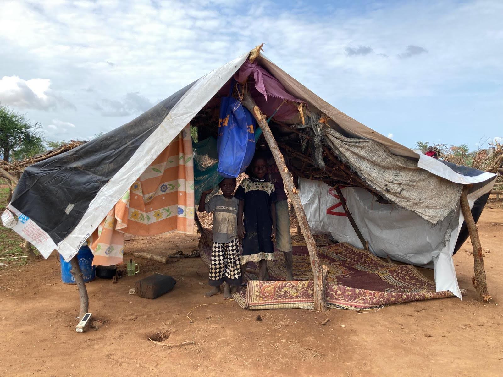 Sudanese children stand under tent made from Meadow Outdoor billboard tarp